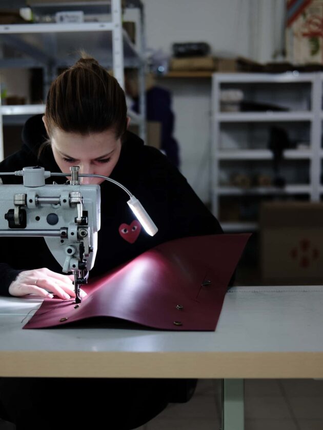 woman using sewing machine on red material.